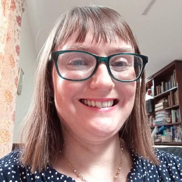 Headshot of a middle-aged white woman wearing her brown hair until her shoulders, rectangular glasses and a blue top